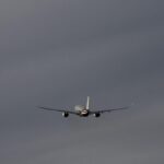Commercial airplane flying through a cloudy sky, representing global summer travel.