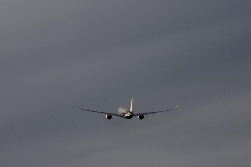 Commercial airplane flying through a cloudy sky, representing global summer travel.