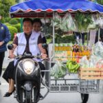 A man drives a motorcycle cart with fresh produce in image_e016d3.jpg, representing Thai consumer confidence drivers.