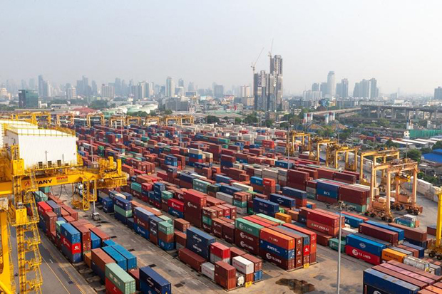 Cargo containers at a major shipping port handling trade logistics crucial for national car production exports.