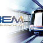 An underground metro train traveling through a tunnel next to the official BEM corporate brand logo.